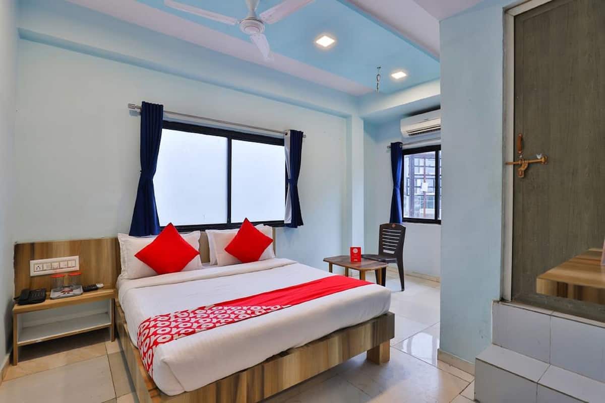A hotel room with a bed, a bedside table, a chair, and a window with curtains.