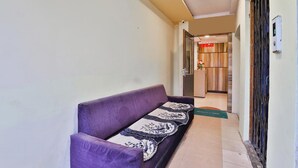 Ein Flur mit einem violetten Sofa, einer gemusterten Decke und einer grünen Matte.
