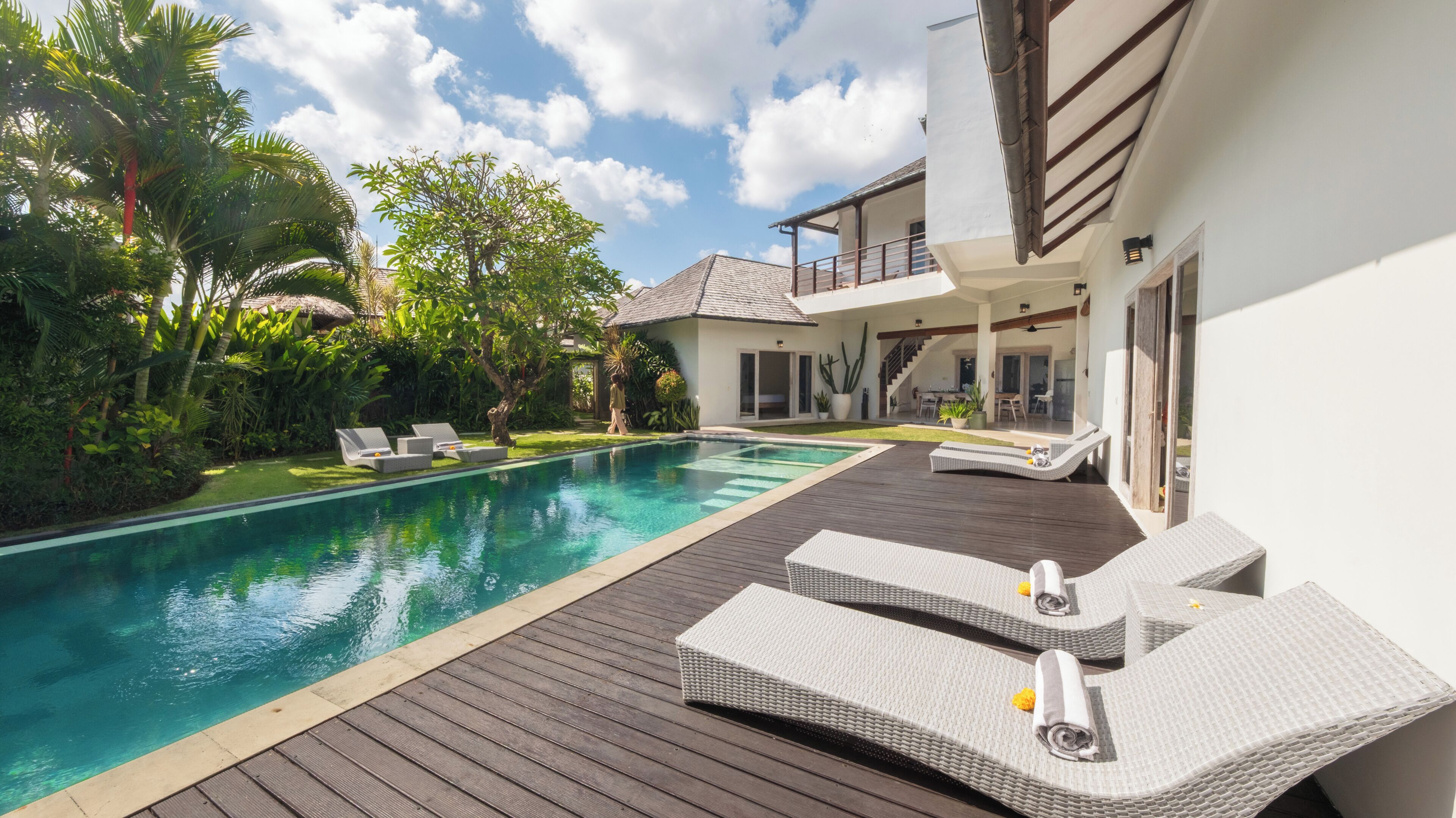 Ein Swimmingpool mit Liegestühlen, eine Holzterrasse und ein Haus mit Balkon.