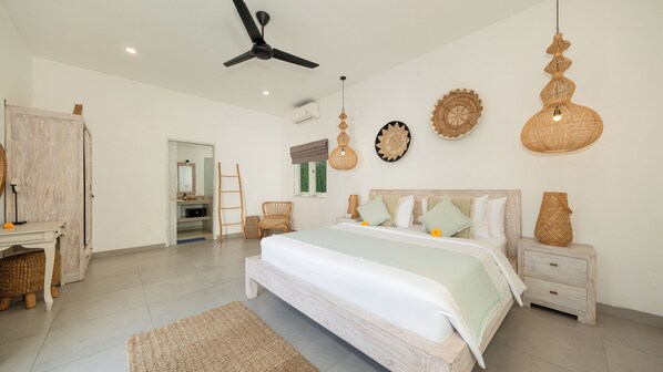 A bedroom with a bed, bedside tables, a wardrobe, a ceiling fan, and wall decorations.