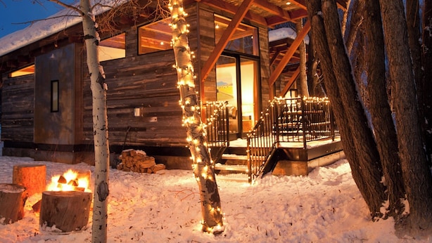 A wooden cabin with a covered porch, surrounded by snow and trees. - Cabin (Modern Rustic Wedge) (Wilson)