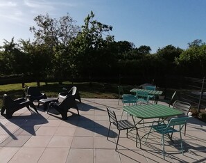 An outdoor patio with green and black metal tables and chairs, surrounded by a tiled floor and a fence. - Spacious LIN Room - Breakfast included (Gavray)