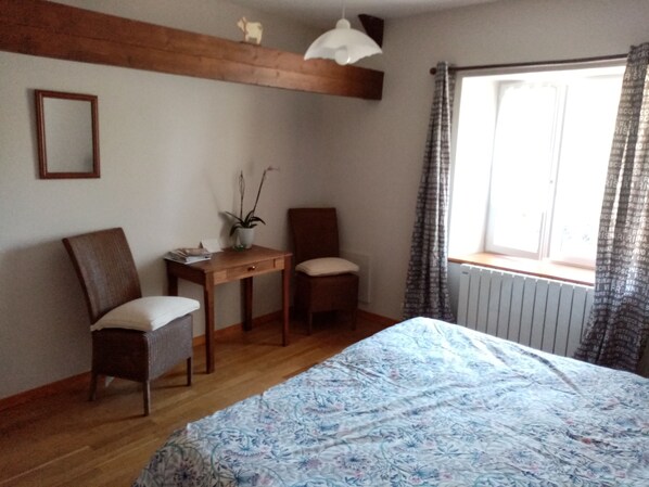 A bedroom with a wooden bed, a desk, two chairs, a potted plant, and a window with curtains. - Spacious LIN Room - Breakfast included (Gavray)