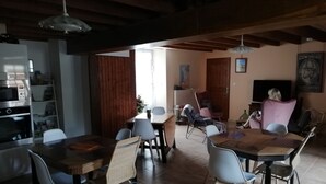 A spacious living area with a dining table, chairs, a television, and a bookshelf.