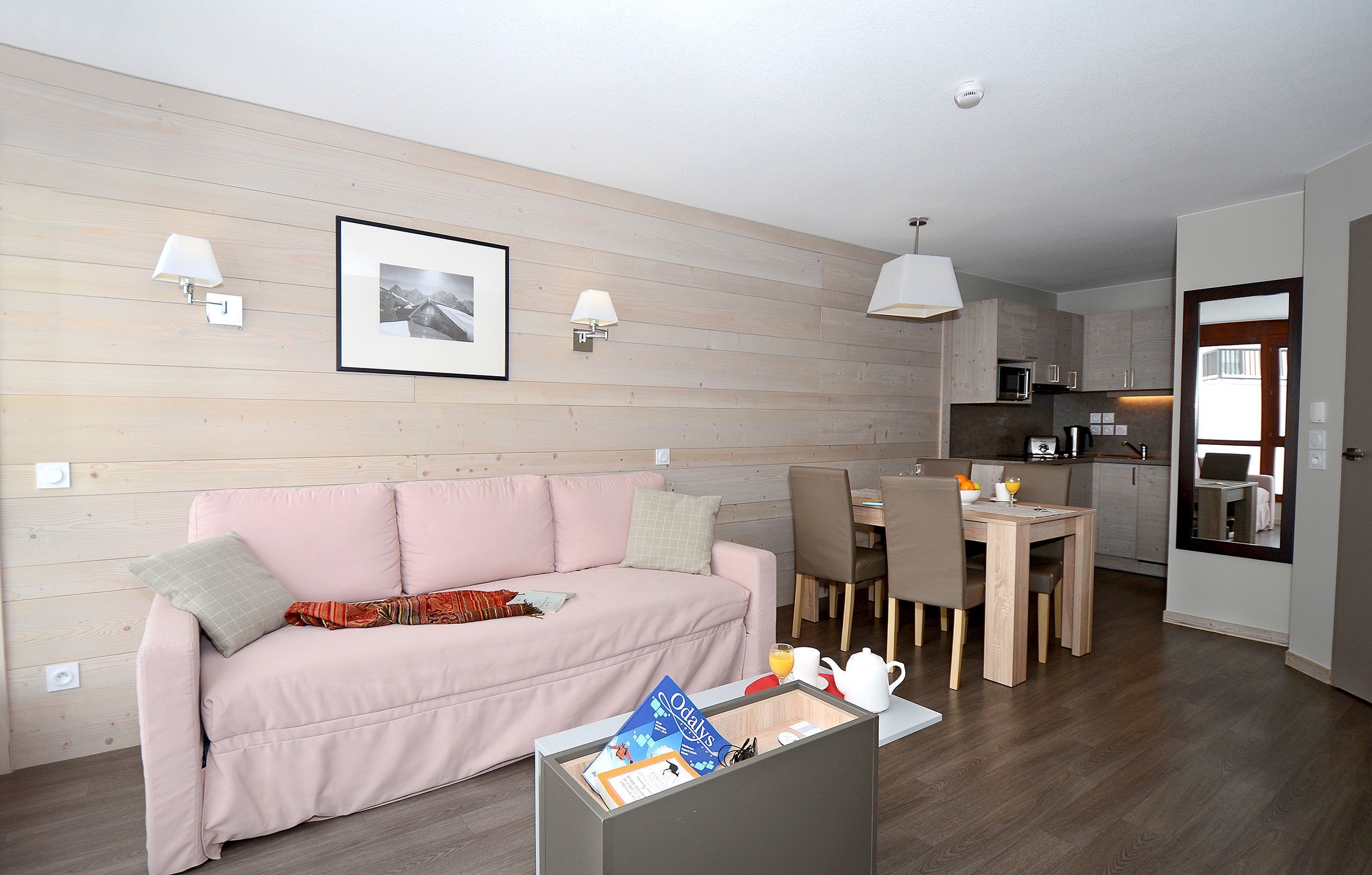 A modern living room with a sofa, dining table, and kitchen area.