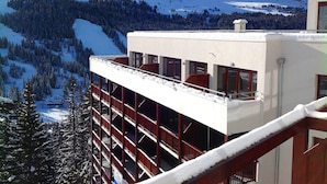A multi-story building with a balcony overlooking a snowy mountain landscape. - Résidence Odalys Le Panoramic (Araches-la-Frasse)