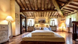 Un dormitorio con piso de madera, una cama con dos almohadas, un radiador y una lámpara.