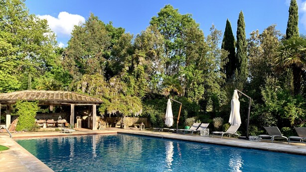 Una piscina con sillones de descanso y un pabellón.