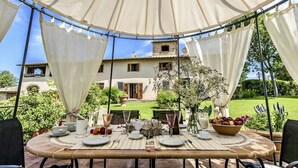 Un área de comedor al aire libre con una mesa dispuesta para dos personas, rodeada por un toldo blanco.