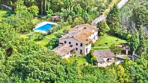 Vista aérea de una extensa propiedad con varias construcciones, una piscina y abundante vegetación.
