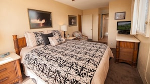 Ein Schlafzimmer mit einem Bett, einem Sessel, einem Fernseher und einem Deckenventilator.