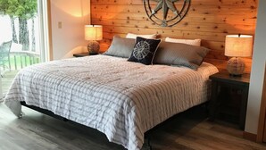 Ein Schlafzimmer mit einem großen Bett, Holzvertäfelung, einer Kompass-Wanddekoration und zwei Nachttischlampen.