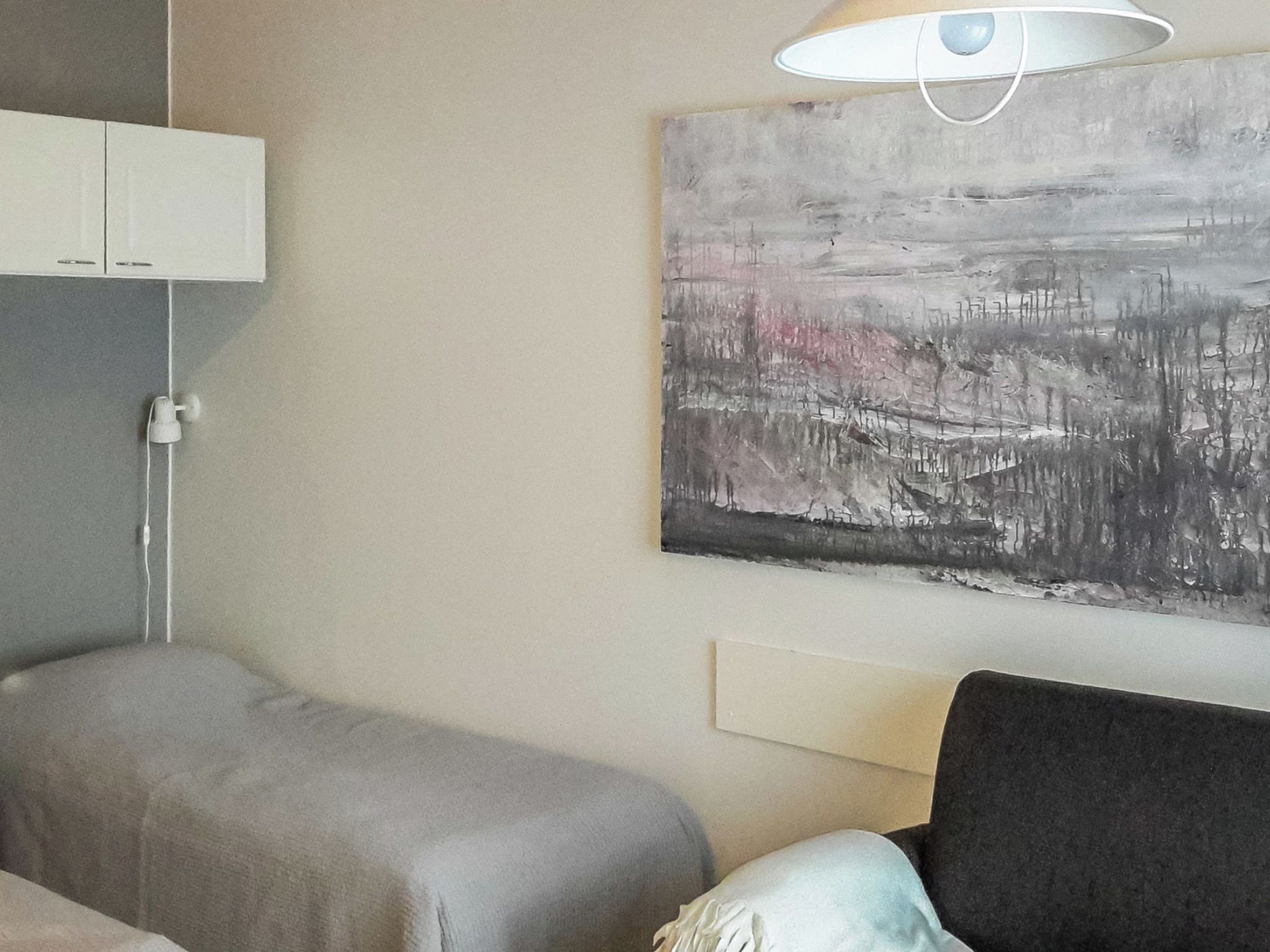 A bedroom with a bed, bedside table, and a wall-mounted lamp.
