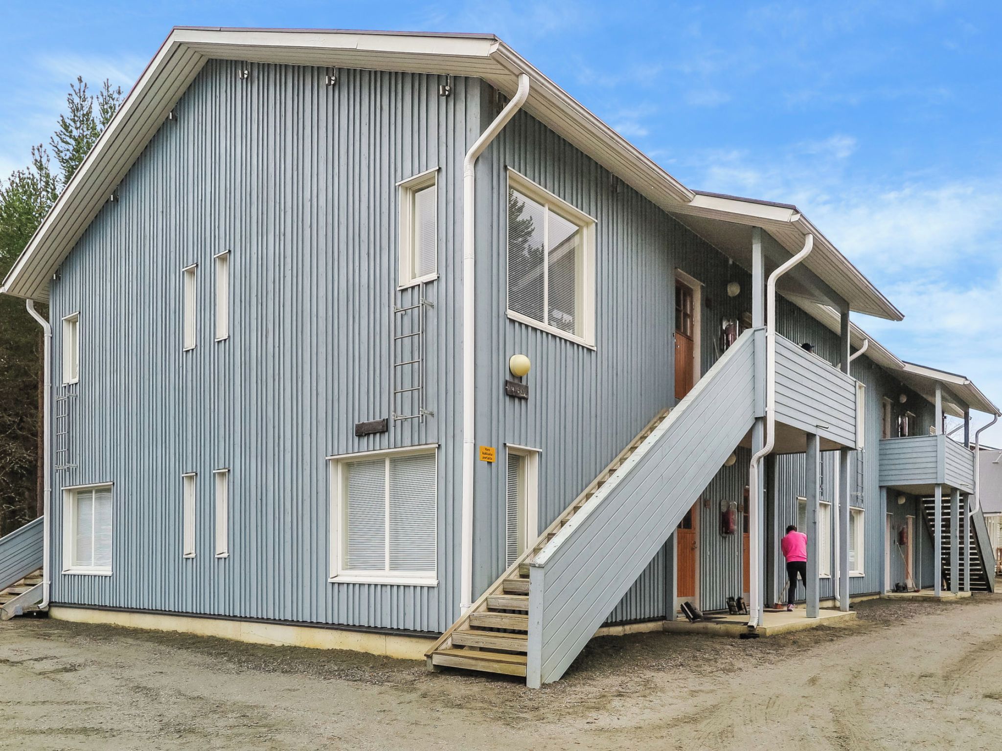 A two-story building with a staircase leading to the second floor, a covered porch, and a small outdoor area.