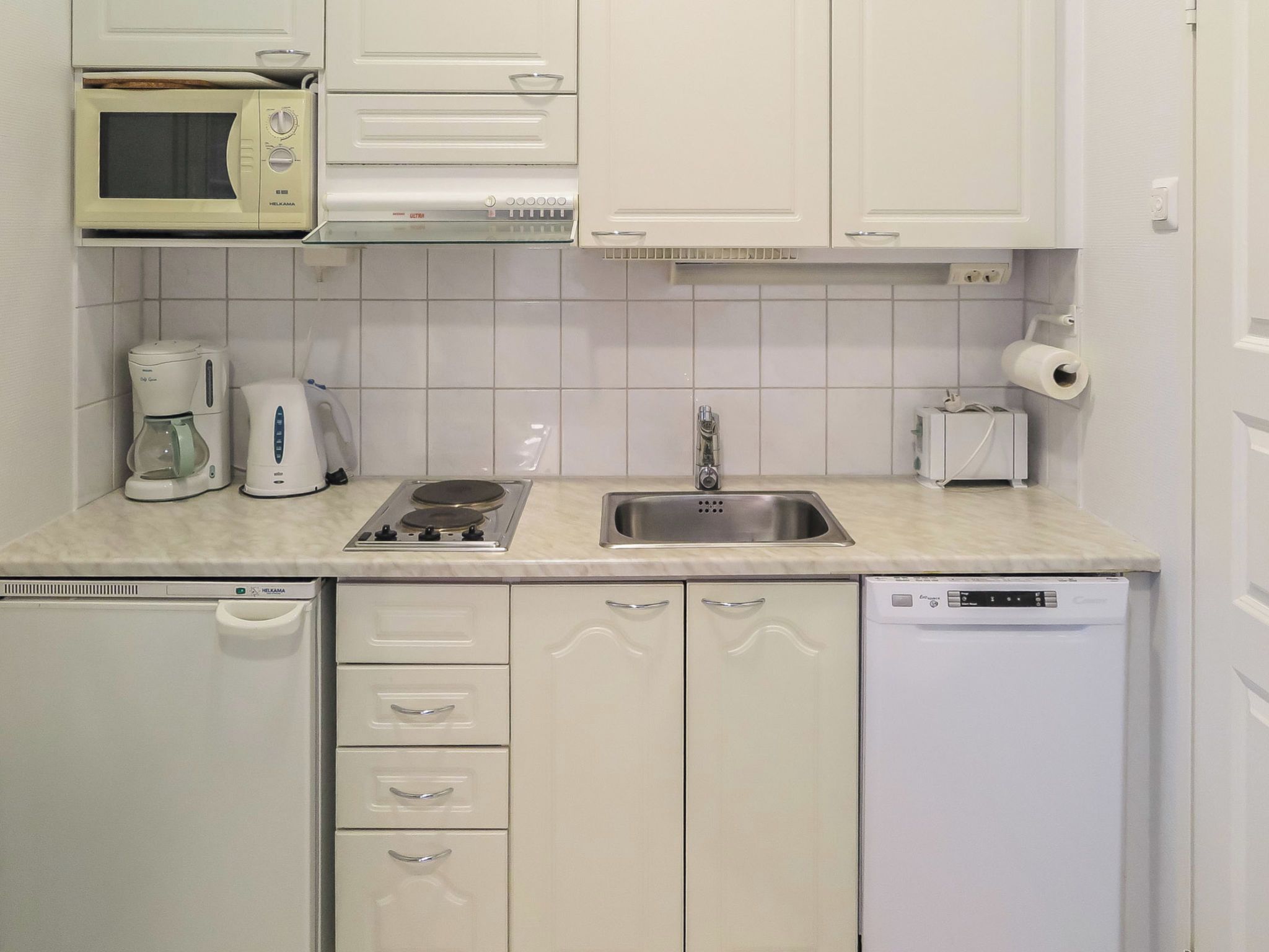 Eine kleine Küche mit Mikrowelle, Kaffeemaschine, Toaster, Spüle und Geschirrspüler.