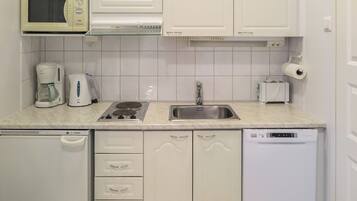 Eine kleine Küche mit Mikrowelle, Kaffeemaschine, Toaster, Spüle und Geschirrspüler.