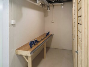 A small, enclosed room with a wooden bench, a metal table, and a door with a metal handle.