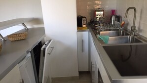 A compact kitchen with a dishwasher, a coffee machine, and a sink. - Three star studio (Sète)