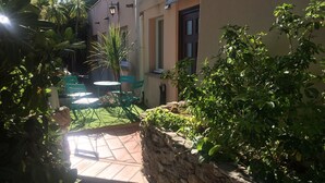 A courtyard with a stone wall, a small table, and chairs. - Three star studio (Sète)