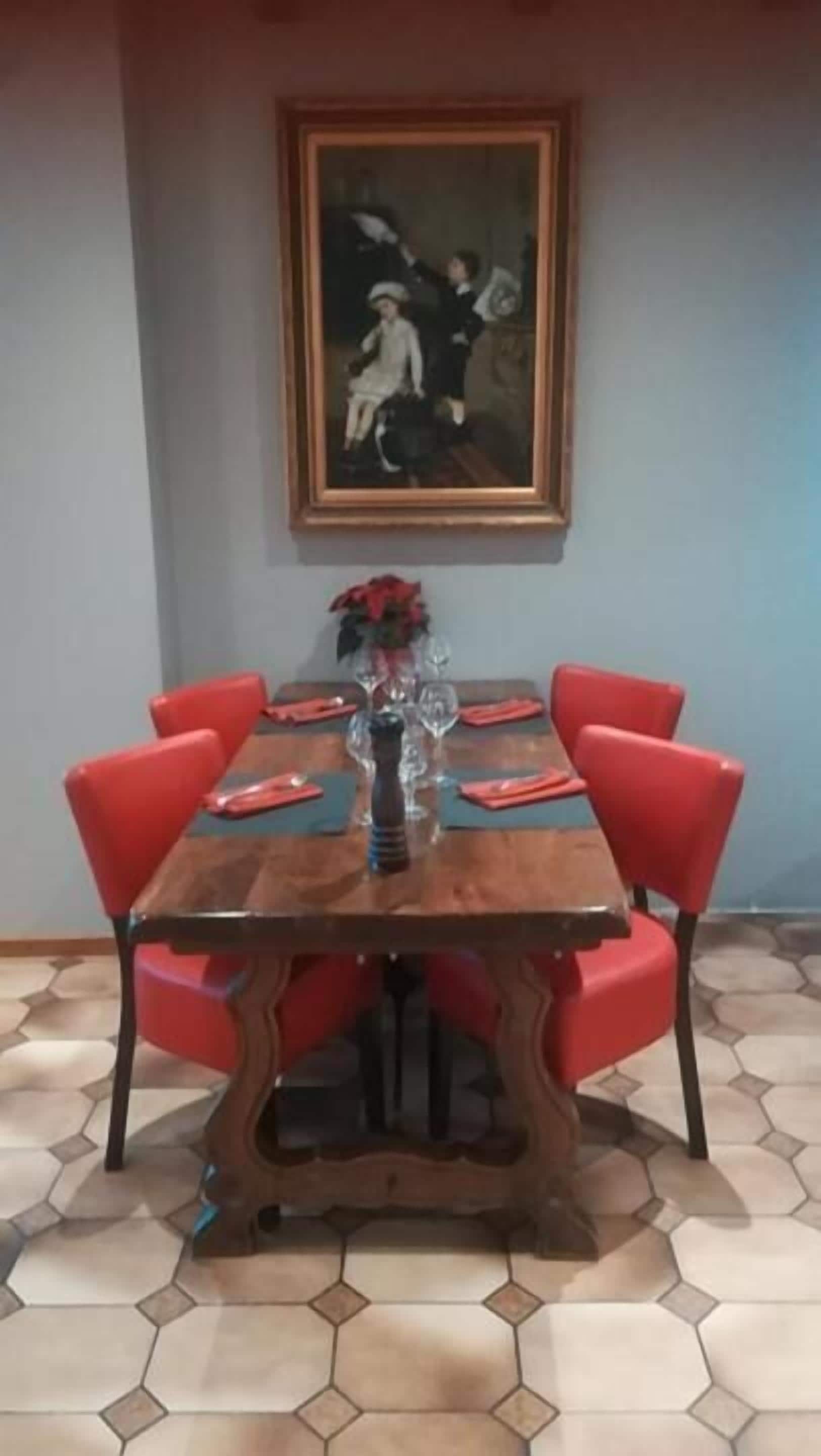 A dining area with a wooden table, red chairs, and a painting on the wall.