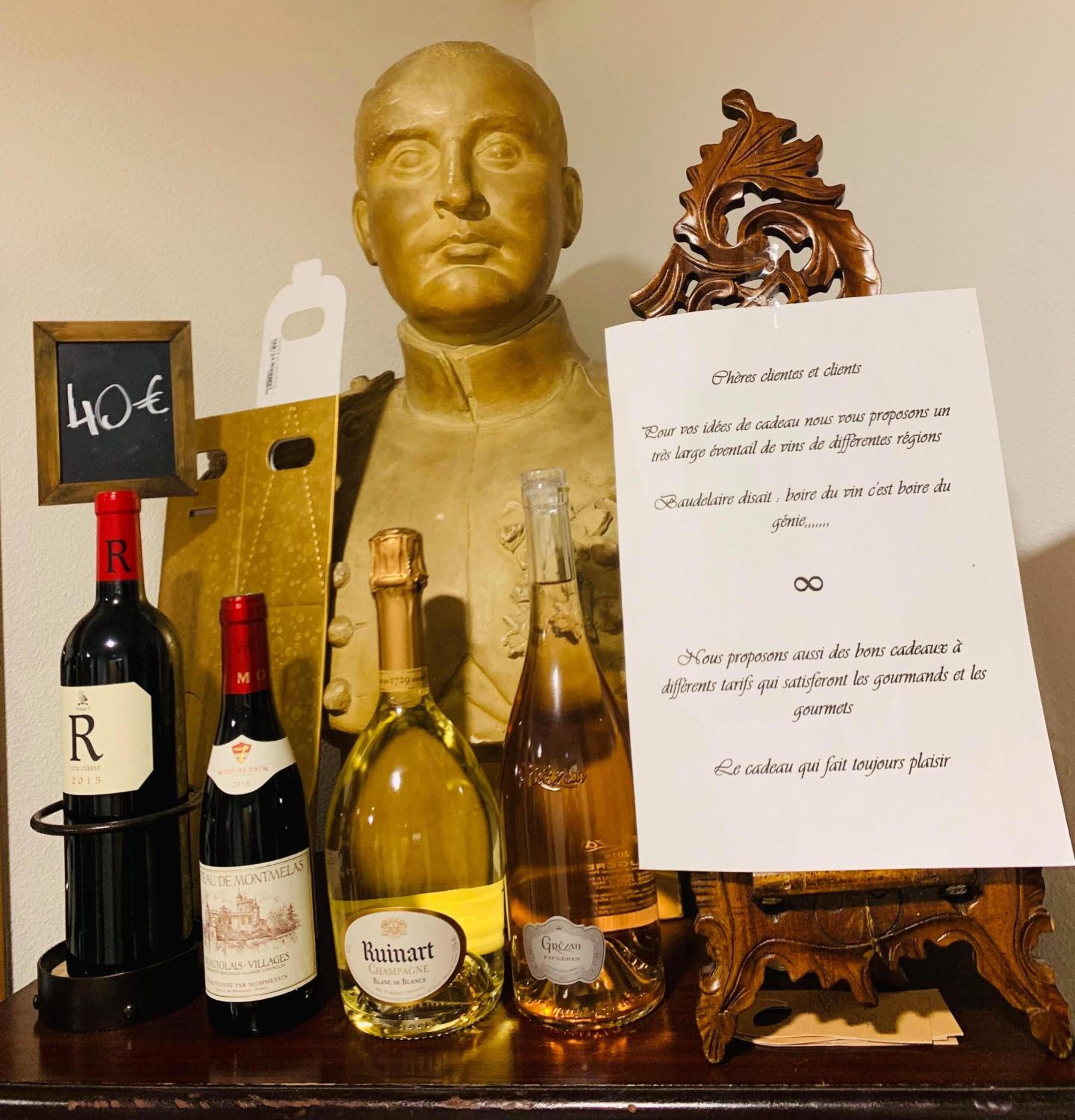 Un présentoir à bouteilles de vin, une étiquette de prix, une sculpture de buste et un menu.