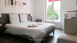 A modern hotel bedroom with a large bed, a bedside table, a chair, and a window with a view of greenery. - Hotel Restaurant Kuentz (Wittersdorf)