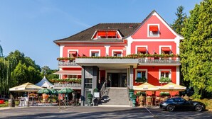 A red building with a balcony, outdoor seating, and a car parked in front. - Hotel Restaurant Kuentz (Wittersdorf)