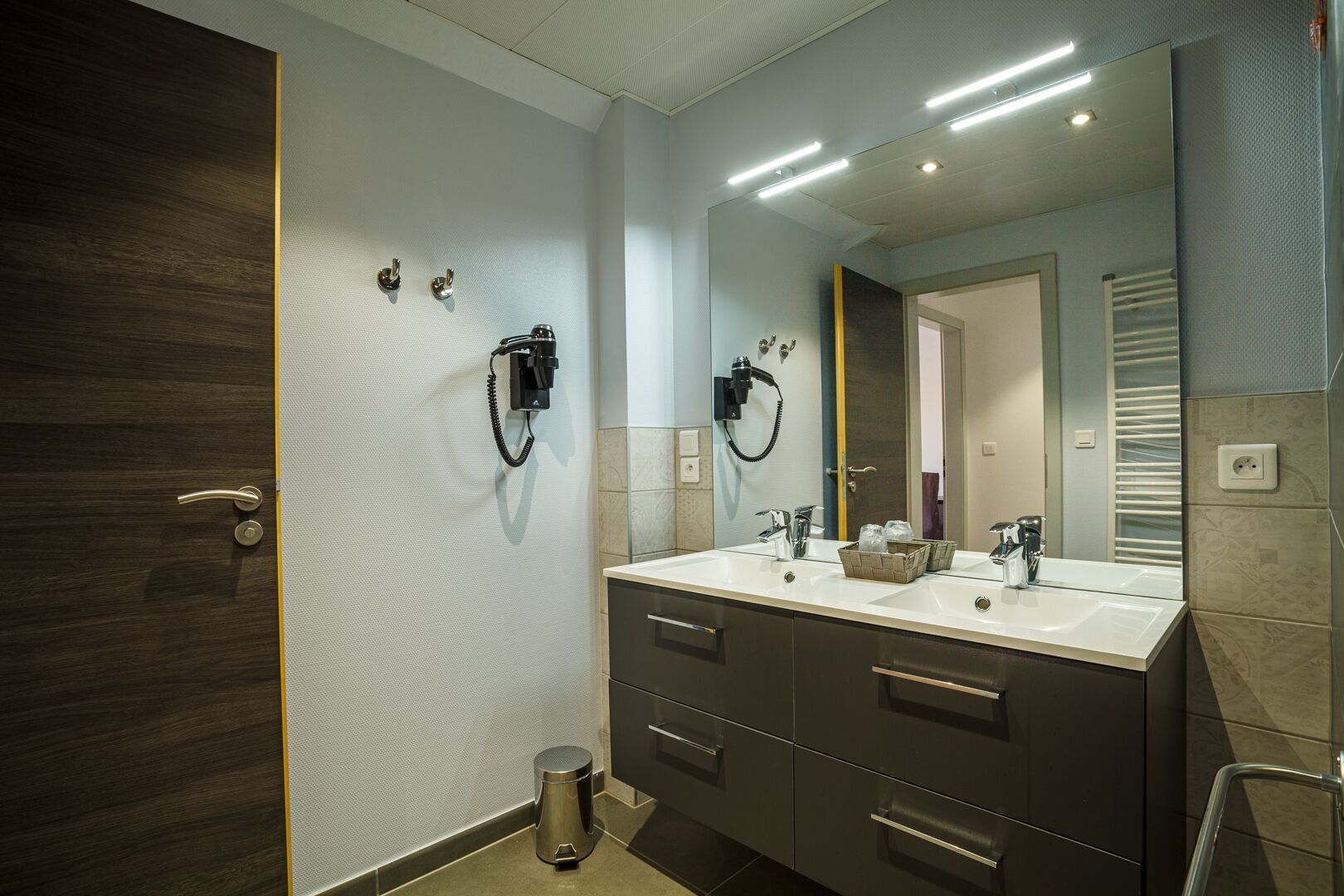 Un bagno moderno con un doppio lavabo, uno specchio grande e due telefoni fissati alla parete.