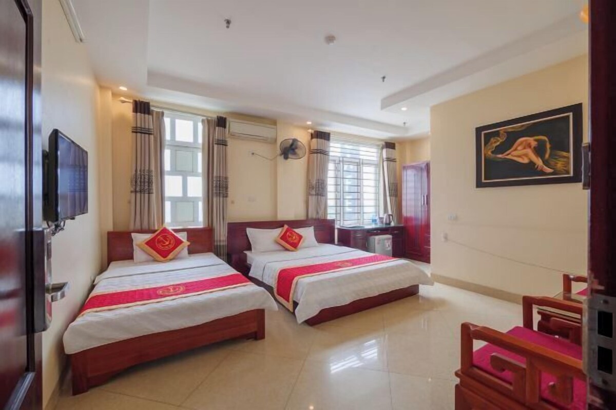 A hotel room with two beds, a TV, a desk, and a chair.