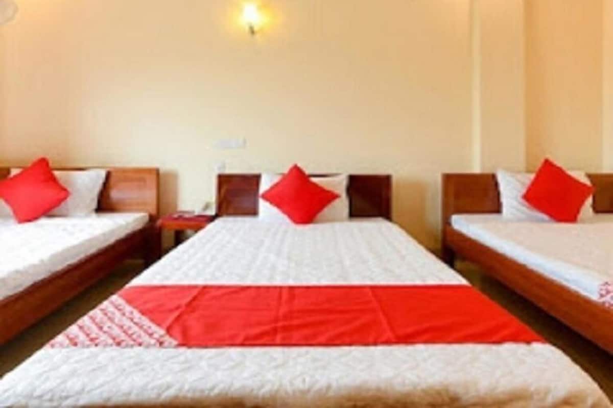 A hotel room with two beds, each with a red pillow, a red blanket, and a wooden headboard.