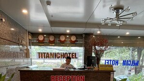 Mostrador de recepción en el TITANICHOTEL, con un reloj, un cartel que indica la recepción y vistas al exterior.