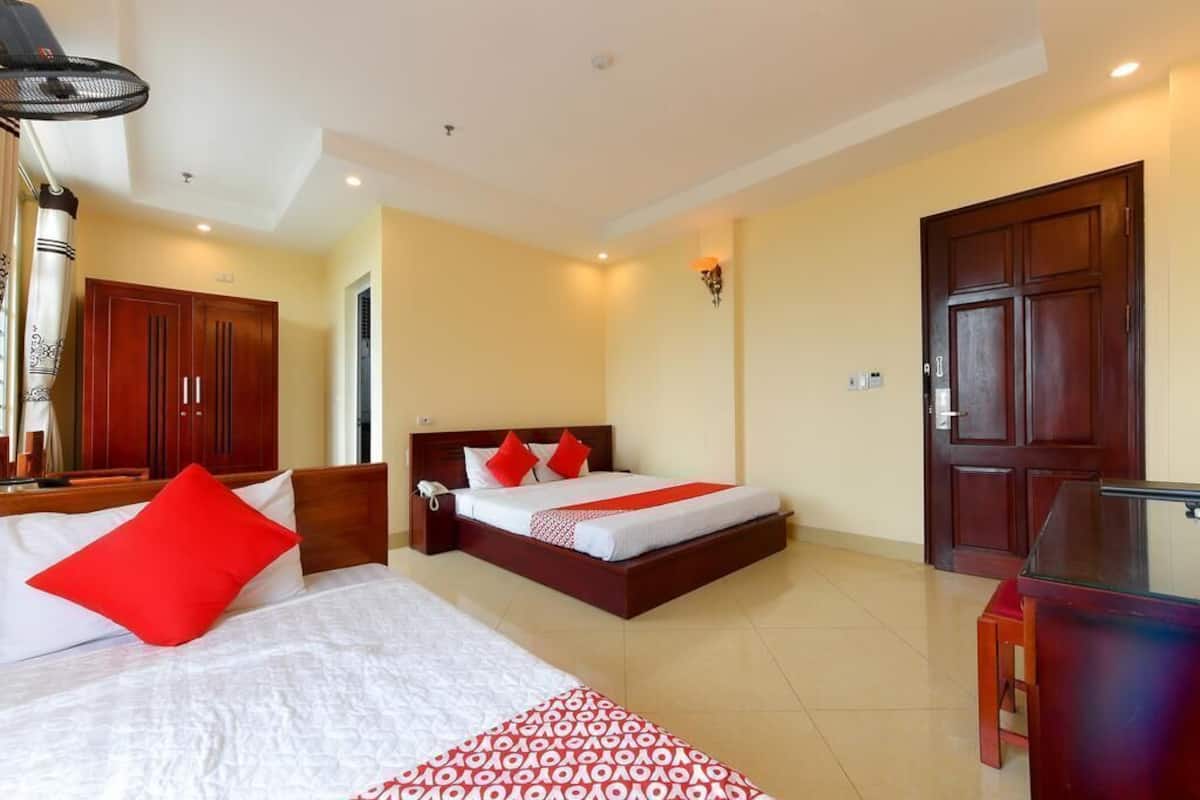 A hotel room with a bed, a desk, a wardrobe, and a door.