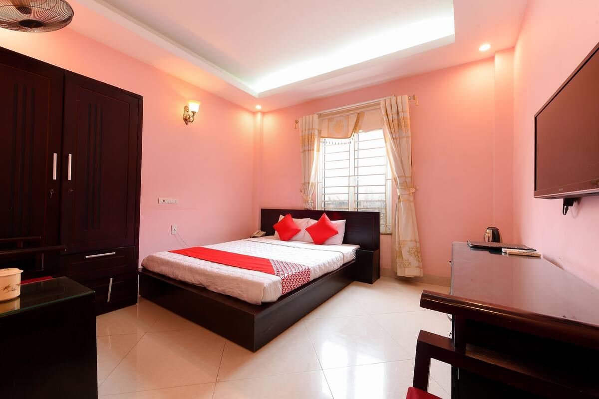 A bedroom with a bed, a desk, a wardrobe, and a television.
