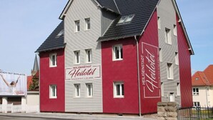 A two-story hotel with a red and grey facade, multiple windows, and a sign reading "Heiligtel." - Heilotel (Heilbad Heiligenstadt)