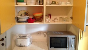 A kitchen with a microwave, shelves with dishes, and a toaster. - Apartment in southern Milan Melegnano (Melegnano)