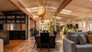 Un'ampia zona giorno con tavolo da pranzo, divani e angolo cottura, caratterizzata da soffitto in legno e travi a vista.
