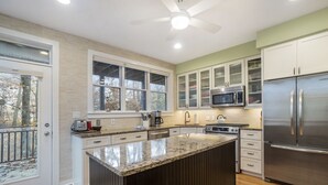 Una cocina moderna con una isla grande, electrodomésticos de acero inoxidable y vistas al exterior.