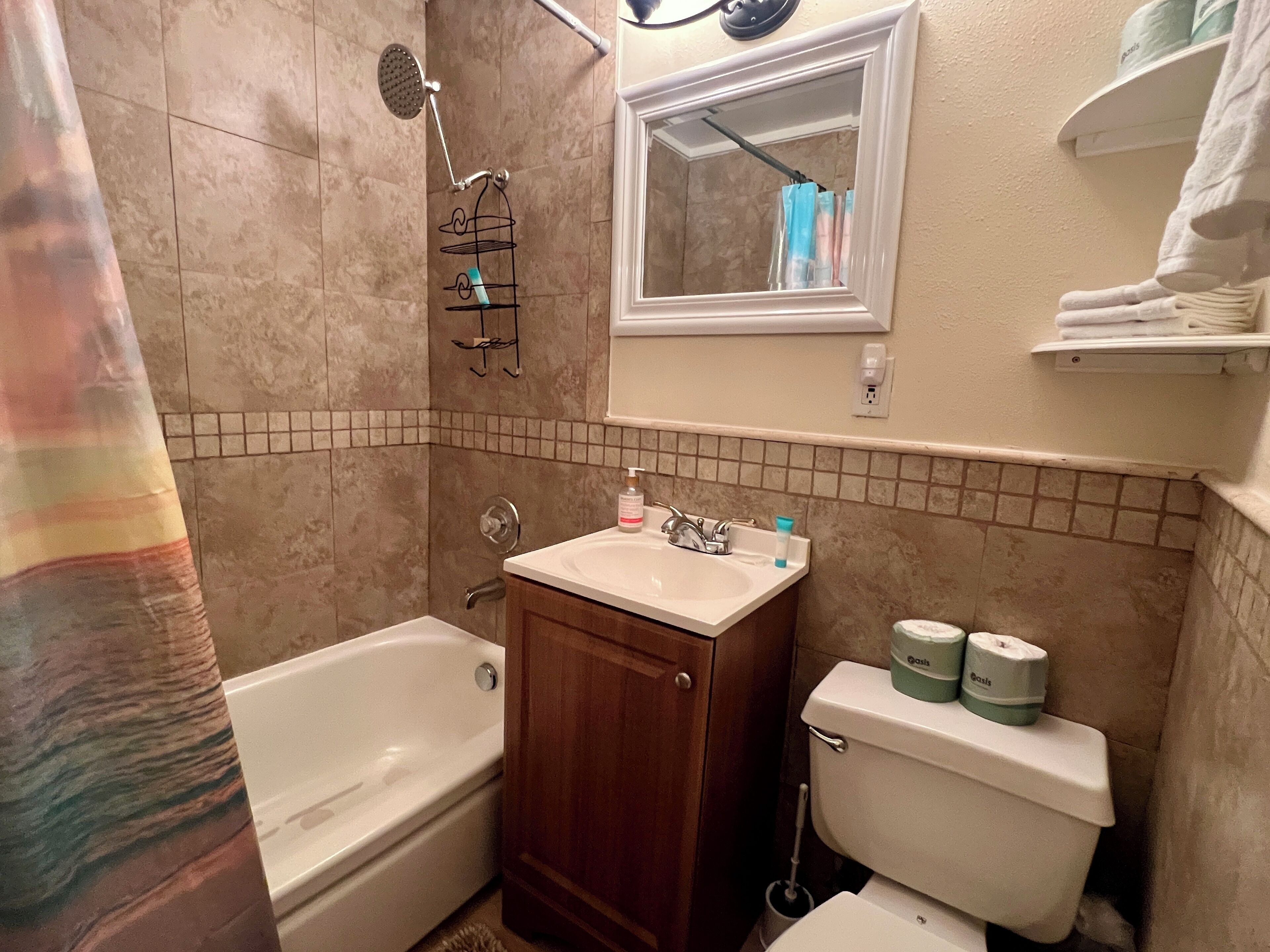 A bathroom with a bathtub, sink, toilet, and a shower area.