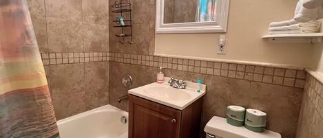 A bathroom with a bathtub, sink, toilet, and a shower area.