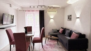 A modern living room with a dining area, a sofa, a TV, and a wall-mounted air conditioner. - Aparthotel Monterria (Bar)