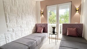 A modern room with a stone accent wall, two grey sofas, a small table, and a window with a view of greenery. - Aparthotel Monterria (Bar)