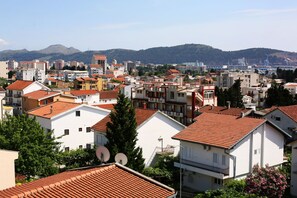 Una zona residencial con varios edificios, algunos con tejados rojos, y montañas al fondo.