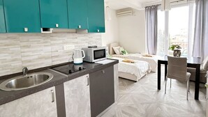 A modern kitchen with teal cabinets, a central island, and a dining area with a table and chairs. - Aparthotel Monterria (Bar)
