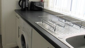 A kitchen with a washing machine, a toaster, and a dish rack.