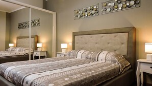 Una camera da letto con un letto grande, due comodini con lampade, uno specchio grande e decorazioni murali.