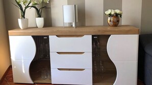 Una cucina moderna con mobili bianchi, un piano di lavoro in legno e vasi decorativi con fiori.