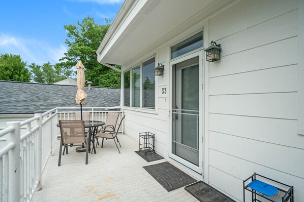 A covered outdoor area with a table and chairs, a number 33 sign, and a door with a window. - Sleepy Hollow Beach Resort introduces Patio 33 (South Haven)