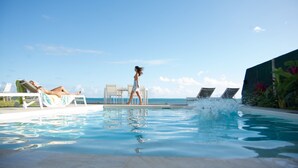 A swimming pool with lounge chairs and a person walking. - Large villa Le Ficus by the sea with swimming pool (PAEA)