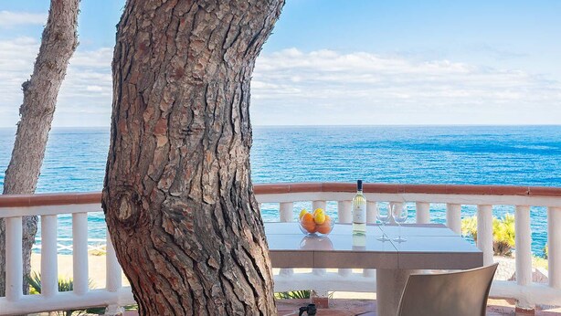 A table with a bottle and glasses, a bowl of fruit, and a view of the sea. - Solemar Sicilia - Residence Mer et Soleil (Bagheria)