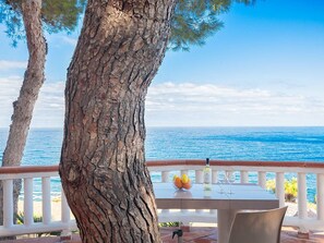 Ein Tisch mit einer Flasche, Gläsern, einer Obstschale und Blick aufs Meer.